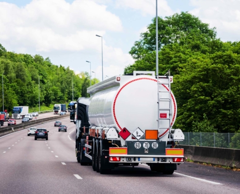 white tanker semi truck driving down a highway