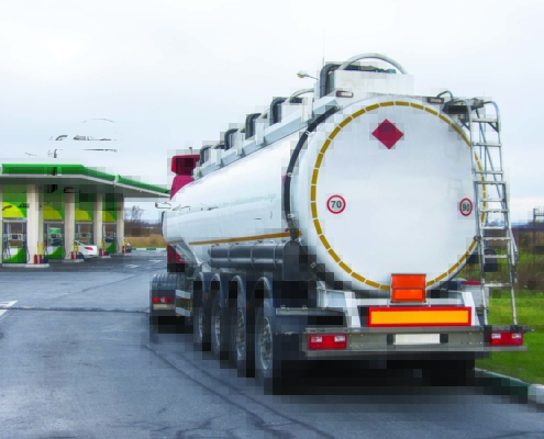 white tanker truck pulling up to a gas station