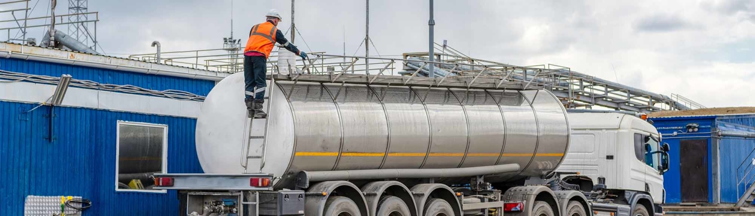 A man performing maintenance at the top of a semi trailer