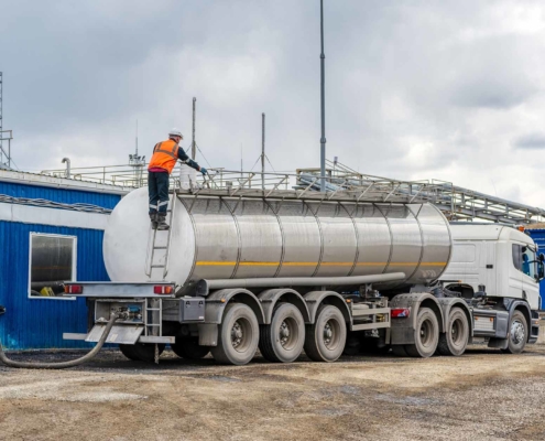 A man performing maintenance at the top of a semi trailer