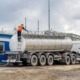 A man performing maintenance at the top of a semi trailer