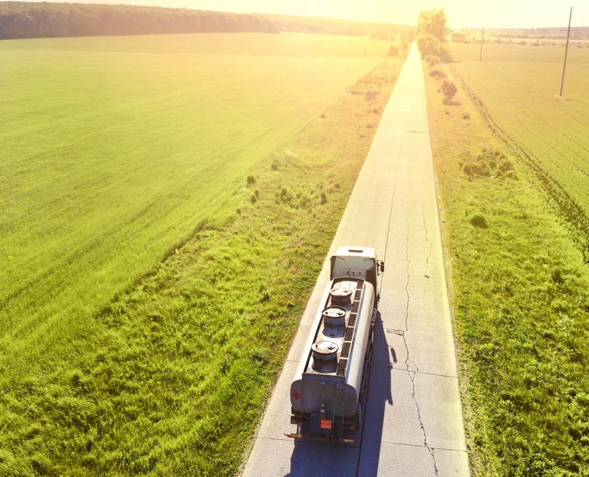 truck driving down a remote country road surrounded by farmland