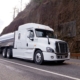 Tanker truck driving down the road around a cliff