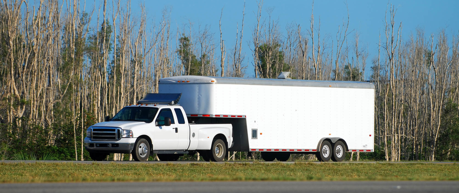 Far side view of white pickup pulling a trailer