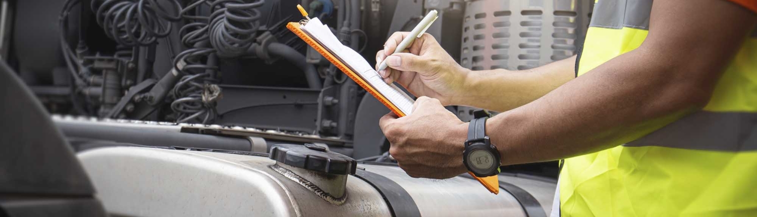 Man wearing a reflective vest and holding a clipboard looking at a truck