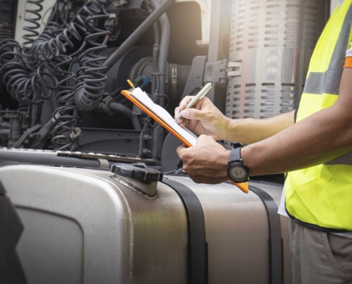 Man wearing a reflective vest and holding a clipboard looking at a truck