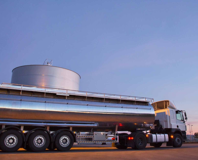 Stainless steel milk tanker next to silage storage tower