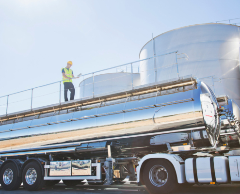 Worker on platform above stainless steel tanker