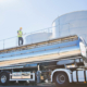 Worker on platform above stainless steel tanker