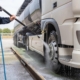 Worker cleaning tank truck with power washer