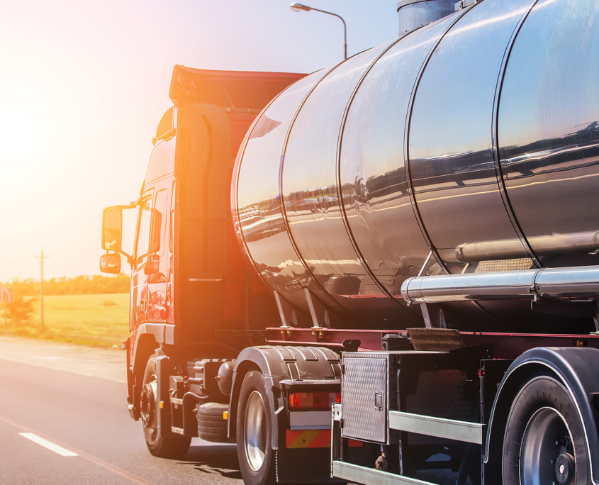 Side view of an oil truck driving down the road at sunset