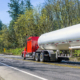 Red big rig classic semi truck transporting cargo in tank semi trailer