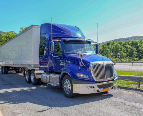 blue truck and white container on high way