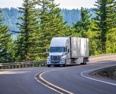 White big rig semi truck transporting goods in refrigerated semi trailer