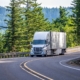 White big rig semi truck transporting goods in refrigerated semi trailer